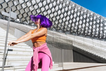 Foto de Bailarina activa despreocupada vistiendo ropa deportiva colorida divirtiéndose en la calle durante el día soleado - Imagen libre de derechos