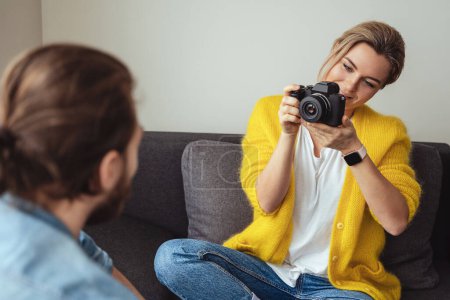 Photo for Young woman photographer taking photos of her boyfriend at home - Royalty Free Image