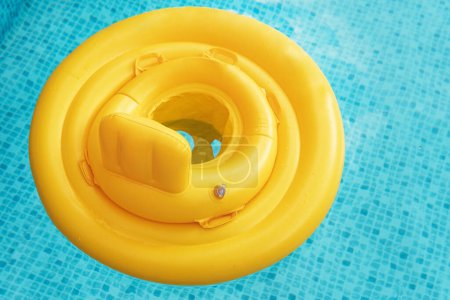 Téléchargez les photos : Bague flottante gonflable jaune pour bébé dans la piscine en plein air - en image libre de droit