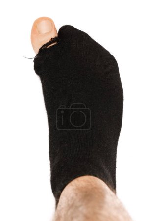 Photo for Closeup shot of a black holey sock on a male foot with toe sticking out on white background. Concept of poverty and financial crisis. - Royalty Free Image
