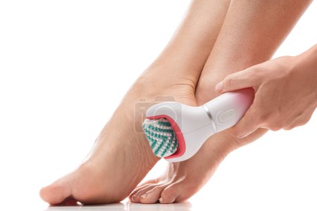 Foto de Primer plano de los pies femeninos y limpiador de pies eléctrico o dispositivo de masaje sobre fondo blanco - Imagen libre de derechos