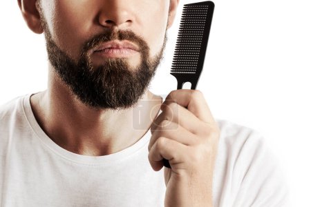 Foto de Hombre peinando su gruesa barba sobre fondo blanco - Imagen libre de derechos
