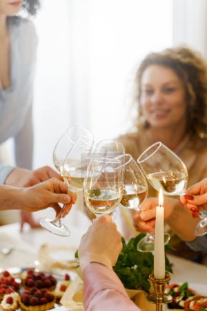 Téléchargez les photos : Jeunes femmes heureuses amis cliquetis verres à la table festive décorée de bougies. - en image libre de droit