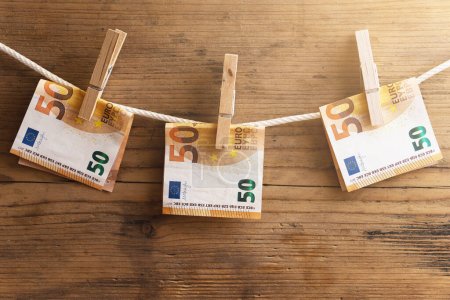 Photo for Fifty euro banknotes are drying on a white rope, held by clothespins. Councept of money saving or money laundering. - Royalty Free Image