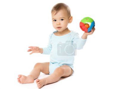 Photo for Adorable little boy in a romper is sitting and playing with plastic toy on white background. - Royalty Free Image