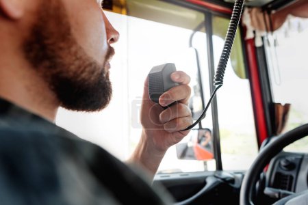 Téléchargez les photos : Chauffeur de camion masculin parlant par CB système radio dans son véhicule - en image libre de droit