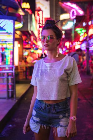 Foto de Retrato de mujer joven y elegante en la calle de la ciudad con luces de neón - Imagen libre de derechos