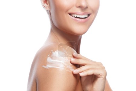 Photo for Young and beautiful woman with applying moisturizing cream on her shoulder over white background - Royalty Free Image