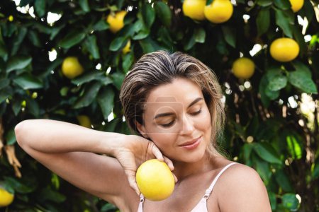 Photo for Outdoor portrait of beautiful woman with smooth skin with a lemon fruit in her hands - Royalty Free Image