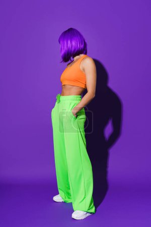 Foto de Retrato de mujer joven con ropa deportiva de colores sobre fondo púrpura - Imagen libre de derechos