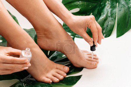 Foto de Primer plano de pies femeninos húmedos y botella de aceite de cutícula nutritivo con gotero - Imagen libre de derechos