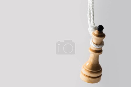 Foto de Primer plano de una reina de ajedrez de madera cuelga de una cuerda blanca. Concepto de enfrentar dificultades en la vida y ser agobiado por la responsabilidad. - Imagen libre de derechos