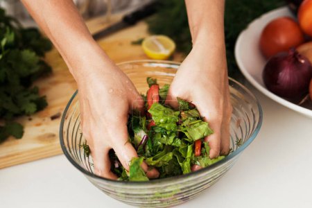 Foto de Primer plano de las manos femeninas mezclando ensalada vegetariana en el bowl - Imagen libre de derechos