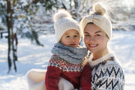 Foto de Retrato de la madre feliz y su lindo hijo pequeño usando suéteres calientes durante el día de invierno soleado - Imagen libre de derechos