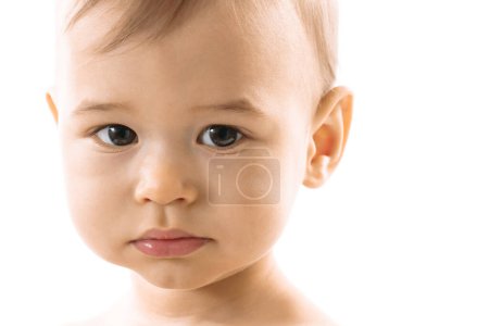 Téléchargez les photos : Gros plan du visage d'un adorable petit garçon sérieux sur fond blanc. - en image libre de droit