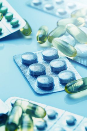 Téléchargez les photos : Gros plan de différentes pilules et capsules en lumière bleue médicale - en image libre de droit