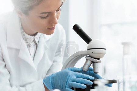 Téléchargez les photos : Une étudiante utilise un microscope dans un laboratoire pendant des travaux de recherche scientifique - en image libre de droit