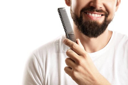 Téléchargez les photos : Homme peignant sa barbe épaisse sur fond blanc - en image libre de droit