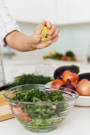 Photo for Closeup of female hands squeezing and adding lemon juice to vegetarian salad - Royalty Free Image