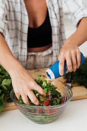 Photo for Closeup of female hands mixing vegetarian salad and adding the salt to it - Royalty Free Image
