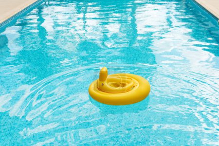 Foto de Sortija inflable amarilla del flotador del bebé en piscina al aire libre - Imagen libre de derechos