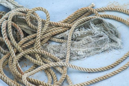 Photo for Closeup shot of shabby coil of nautical rope tangled on the bottom of a fishing boat hull. - Royalty Free Image