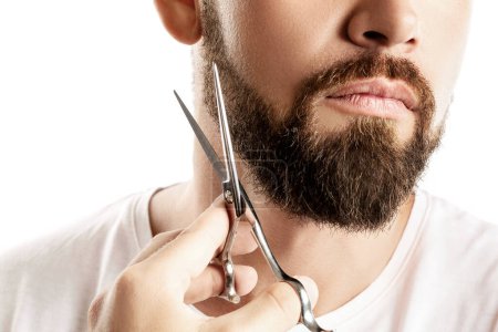 Photo for Man trimming his beard with a scissors on white background - Royalty Free Image
