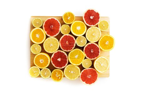 Photo for Different sliced citrus fruits such as grapefruit, orange, lemon and lime on cutting board against white background - Royalty Free Image