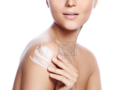 Photo for Young and beautiful woman with applying moisturizing cream on her shoulder over white background - Royalty Free Image