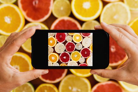 Photo for Closeup of female hands with smartphone taking photos of different citrus fruits - Royalty Free Image