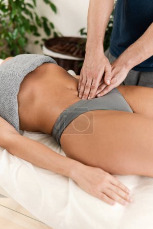 Téléchargez les photos : Gros plan des mains de masseur homme pendant le massage de l'estomac pour sa cliente - en image libre de droit