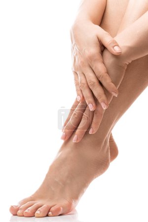 Foto de Primer plano de pies y manos femeninas con piel suave, manicura francesa y pedicura sobre fondo blanco - Imagen libre de derechos