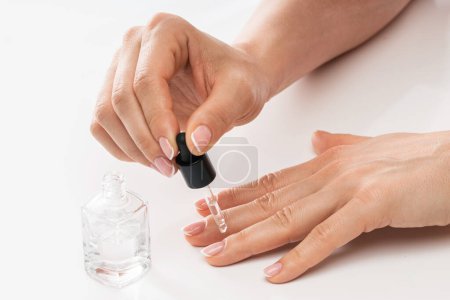 Téléchargez les photos : Mains féminines et bouteille d'huile de cuticule nourrissante avec compte-gouttes sur fond blanc - en image libre de droit