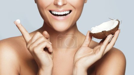 Photo for Young smiling woman using moisturizing cream based on coconut oil - Royalty Free Image