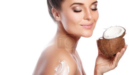 Photo for Young beautiful woman applying cream on her body based on coconut oil on white background - Royalty Free Image