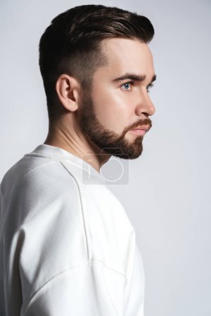 Photo for Handsome bearded man wearing white sweatshirt against gray background - Royalty Free Image