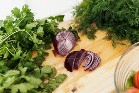 Photo for Closeup of red onion and green herbs on wooden cutting board - Royalty Free Image