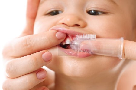 Primer plano de una madre bromeando suavemente los dientes de su hijo pequeño con un cepillo de dientes