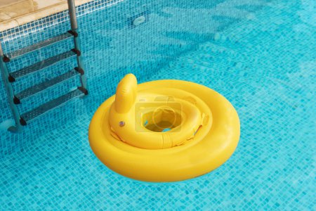 Foto de Sortija inflable amarilla del flotador del bebé en piscina al aire libre - Imagen libre de derechos