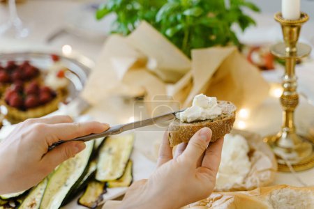 Foto de Primer plano de una mujer haciendo un sándwich de queso crema en la mesa festiva. - Imagen libre de derechos