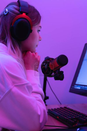 Foto de Blogger joven usando micrófono de condensador durante podcast en línea en la habitación con luz de neón - Imagen libre de derechos