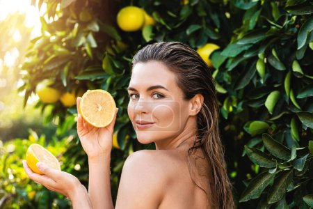 Photo for Outdoor portrait of beautiful woman with smooth skin with a lemon fruit in her hands - Royalty Free Image