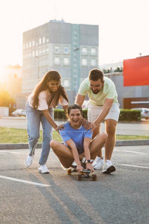 Téléchargez les photos : Trois amis insouciants divers s'amuser et monter longboard sur le parking - en image libre de droit