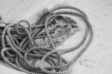 Téléchargez les photos : Gros plan noir et blanc de bobine minable de corde nautique enchevêtrée au fond d'une coque de bateau de pêche. - en image libre de droit