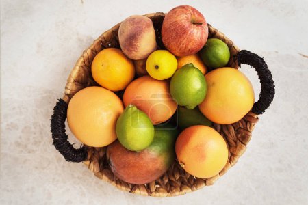 Téléchargez les photos : Panier plein de fruits différents tels que pomme, pêche, orange, citron pamplemousse et mangue - en image libre de droit