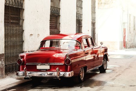 Vista trasera de un coche rojo vintage brillante estacionado en la calle.