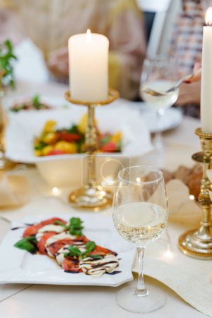Photo for Festive table served for dinner with fresh food and white wine, decorated with candles. - Royalty Free Image