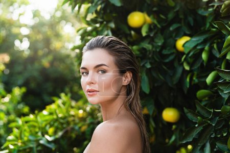 Foto de Retrato al aire libre de mujer hermosa con piel lisa contra limoneros - Imagen libre de derechos