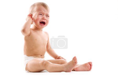 Foto de Adorable niño molesto en pañal está sentado y llorando sobre fondo blanco. - Imagen libre de derechos