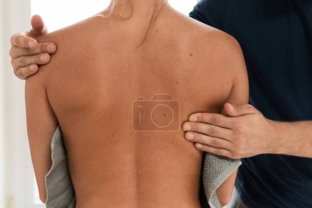 Masseur Mann tut Rückenmassage für seine Kundin in professioneller Massageklinik